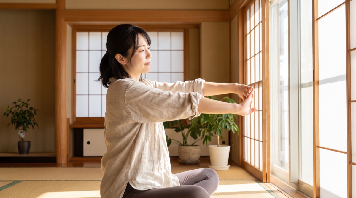 自宅でストレッチをしながら過ごす女性のイメージ