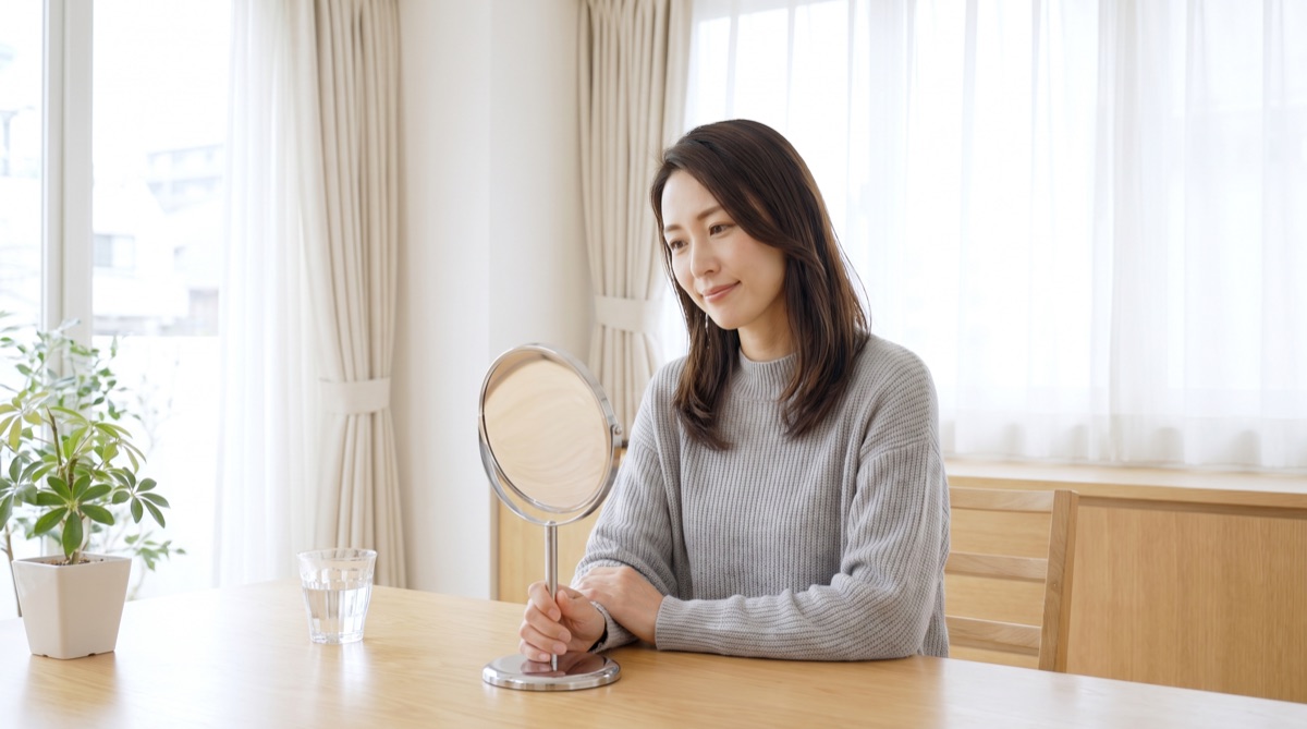 鏡で自分の顔を確認しながら、施術の効果についてカウンセリングを受ける女性