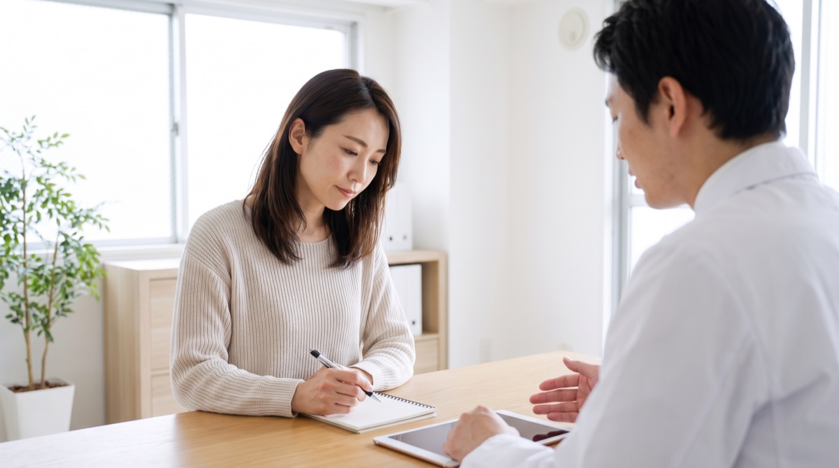カウンセリングでメモを取りながら医師の説明を聞く女性