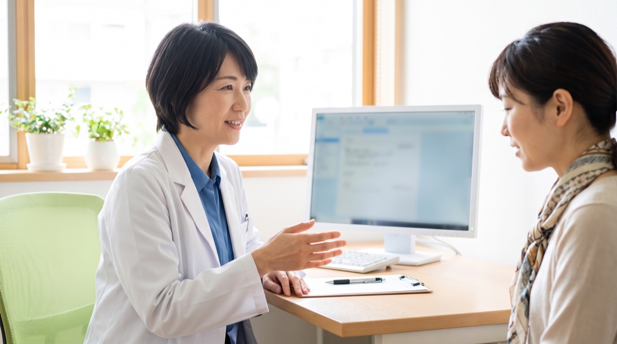 医師がカウンセリング室で患者に資格や所属学会について説明している様子