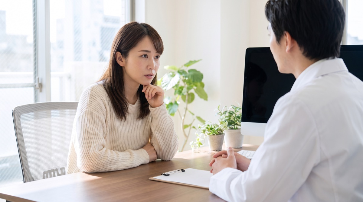 医師の説明を真剣な表情で聞いている女性のカウンセリング風景